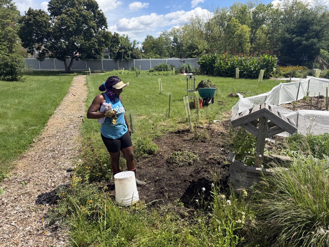 Jerneice carrying a bucket while working among the garden beds
